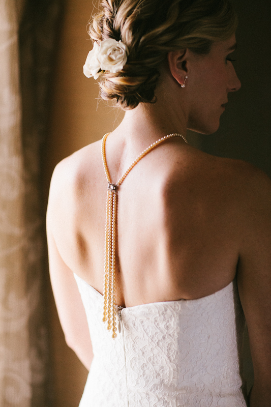 Bride gets ready with a long pearl necklace before her modern outdoor wedding at Morris Arboretum.