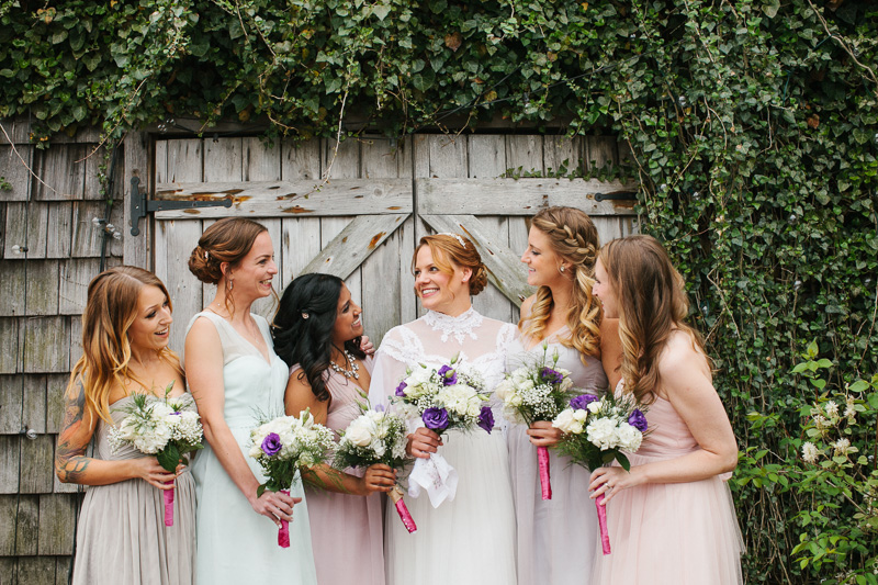 A bride with her bridesmaids take portraits in front of the rustic vintage-inspired Terrain. 