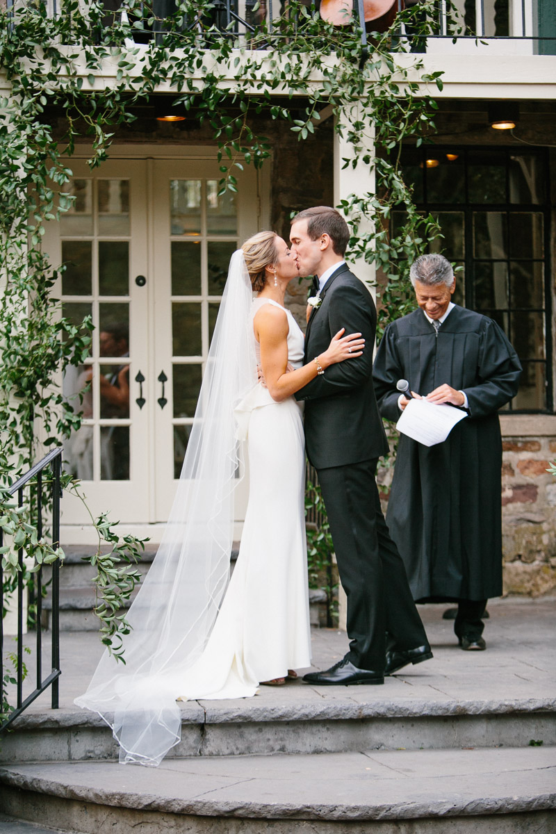 couple kiss at outdoor wedding ceremony in stone courtyard Hollyhedge Estate New Hope