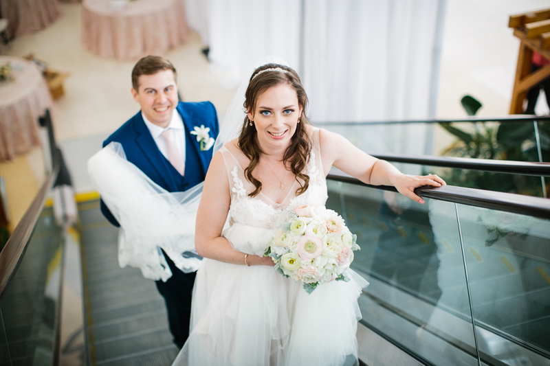 Bride and groom ride the escalator to the top of their high-rise wedding.