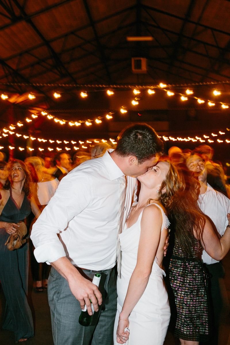 Newlyweds kiss under the string lights at the 23rd Street Armory.