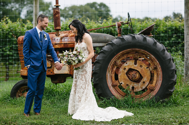 Bride and groom in front of an antique tractor at Grace Winery.