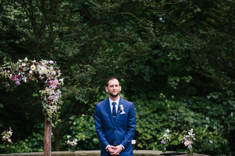 Groom at the altar of this red barn wedding venue. 