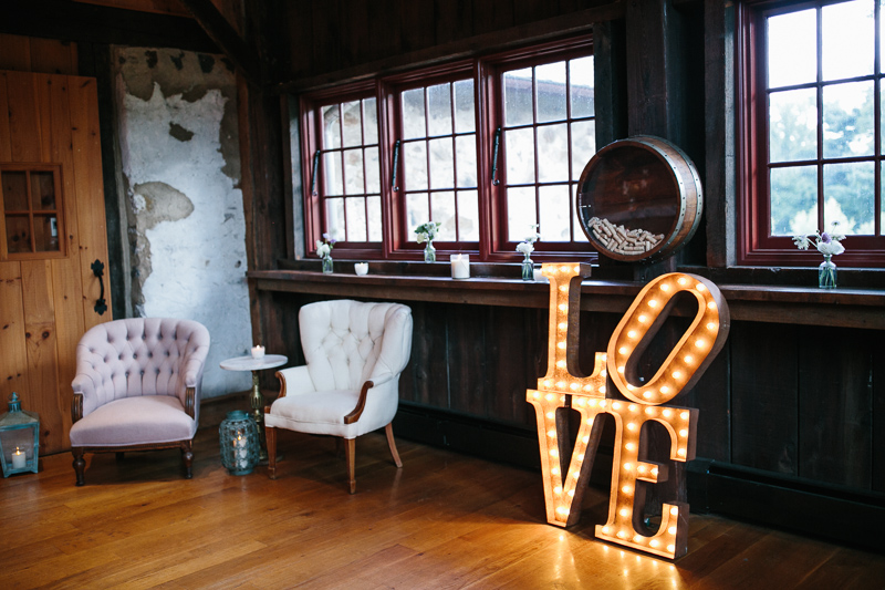 Marquee love sign and luxurious vintage chairs decorate the inside of this rustic barn at Grace Winery. 