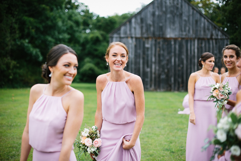 The bridesmaids walk along the grounds of this outdoor farm in New York.