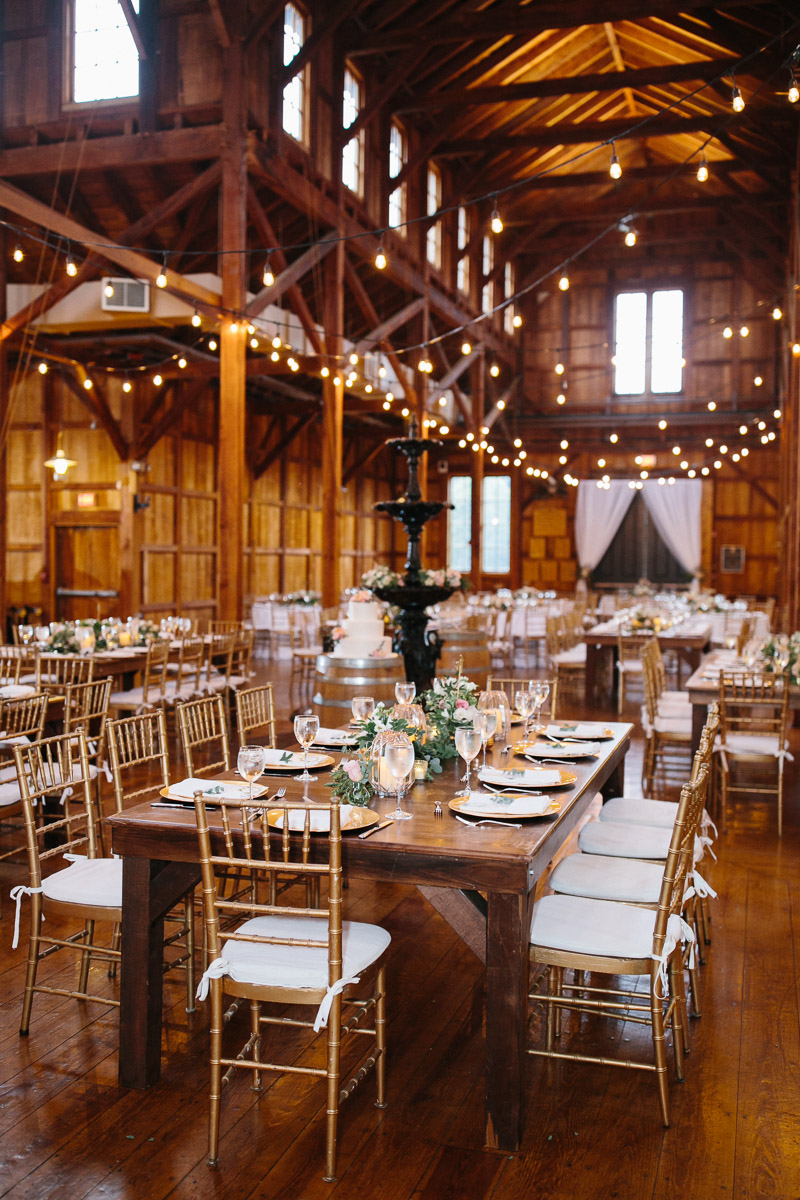 Rustic barn wedding reception decorated with string lights.