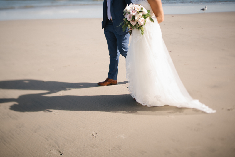 Bride and groom walk down the shore at the Reeds.