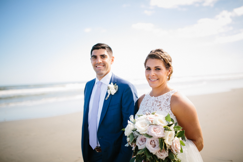 Bride and groom walk along the ocean at the Jersey shore in Stone Harbor.