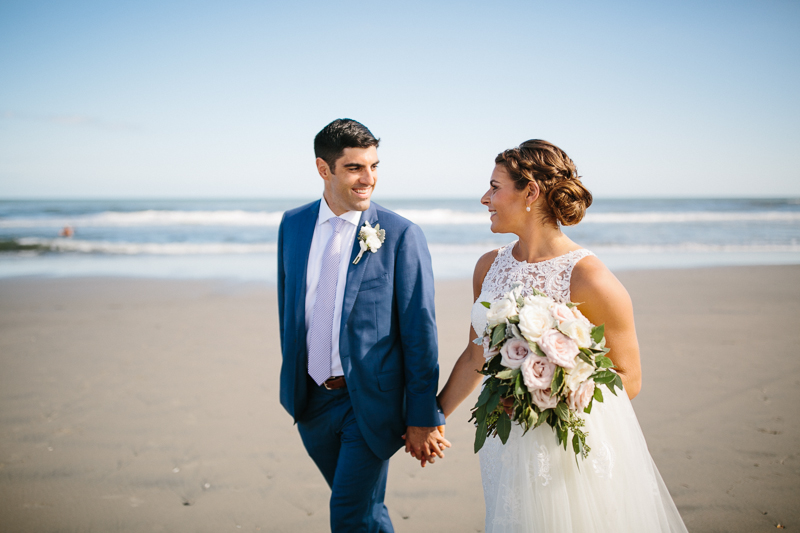 Bride and groom walk along the ocean at the Jersey shore in Stone Harbor.