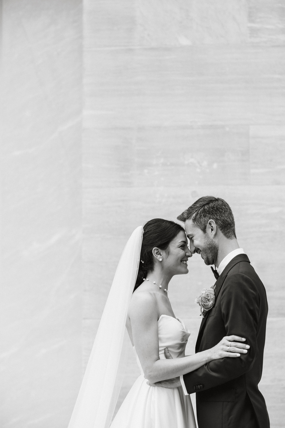 Black and white photo of bride and groom leaned into each other.