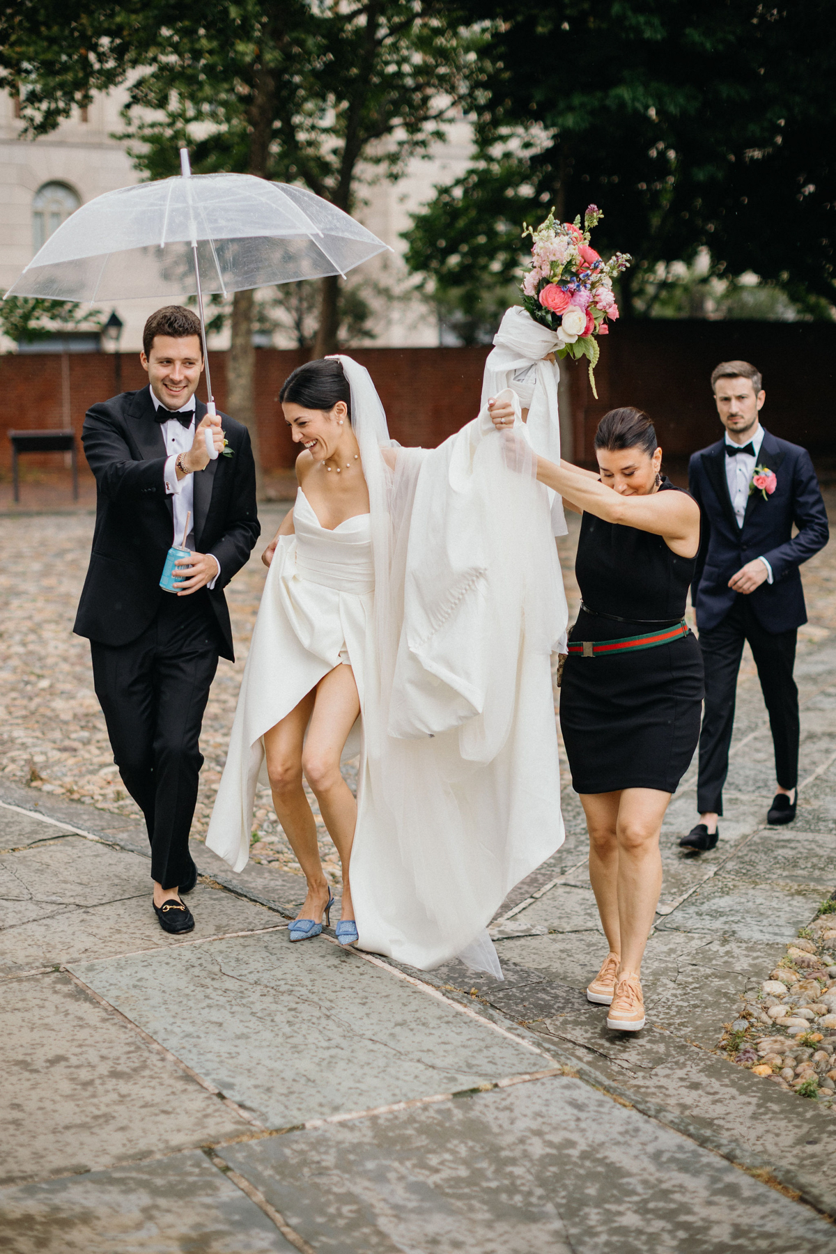 Candid photo of planner holding brides dress as they walk across the alley of the Merchant Exchange Building.