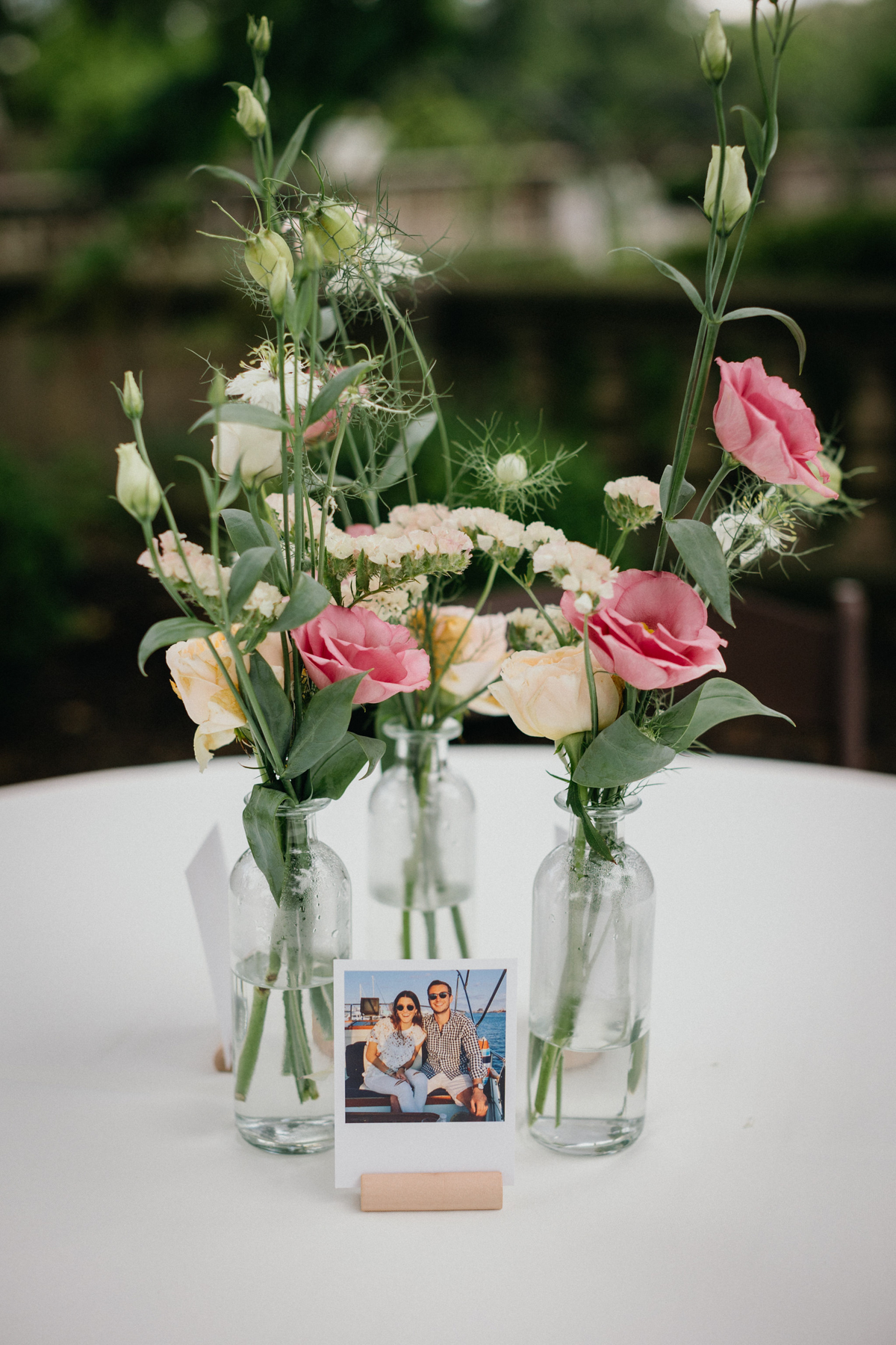 Simple pink and white floral arrangements in clear glass vases on a white table cloth at a Curtis Arboretum wedding.