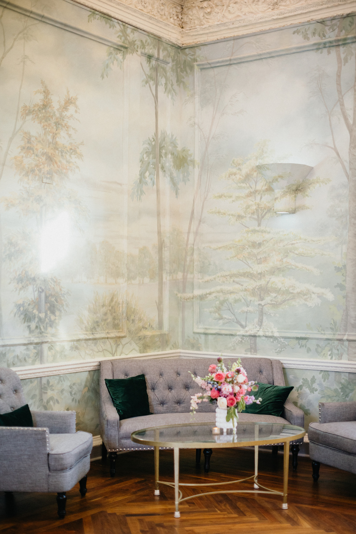 Sitting area at a summer wedding reception with a vintage couch and fresco wall.