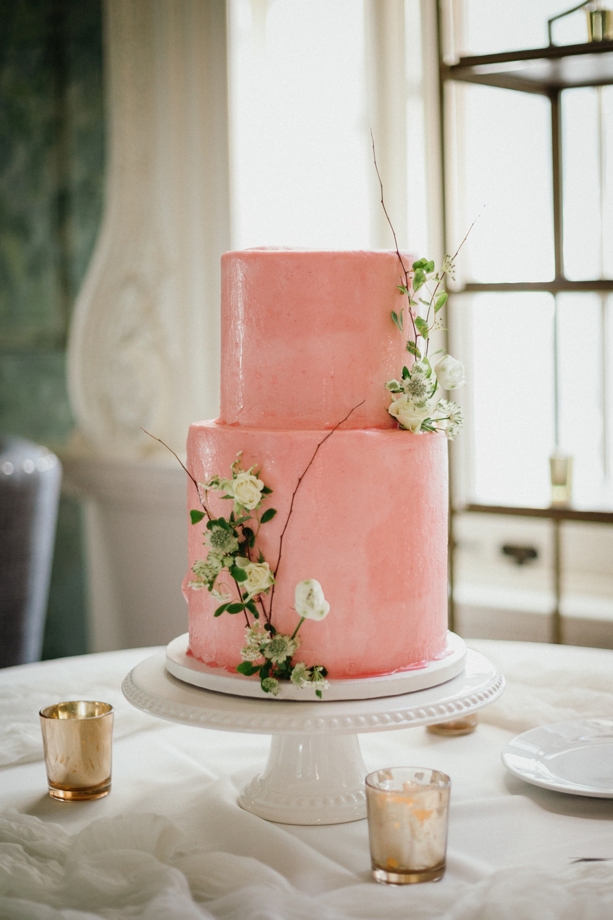 Simple pink wedding cake with white floral details.