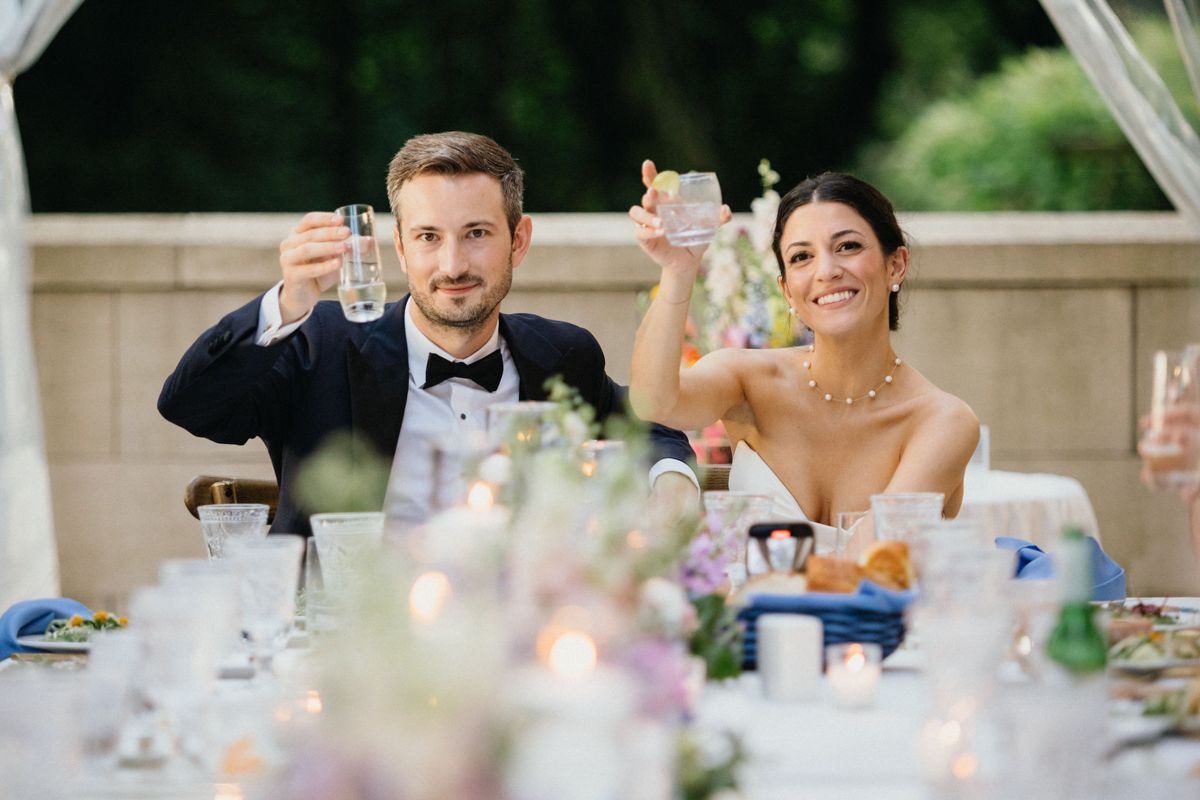 Bride and groom raising their glasses after a speech at an outdoor Curtis Arboretum wedding reception.