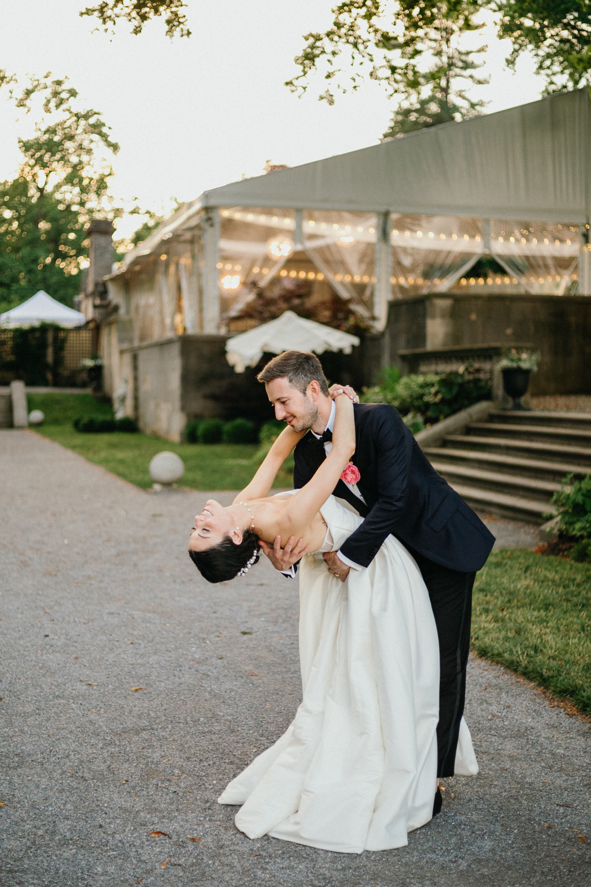 Fun portrait of groom dipping bride on a stone path in the gardens at a Curtis Arboretum wedding.