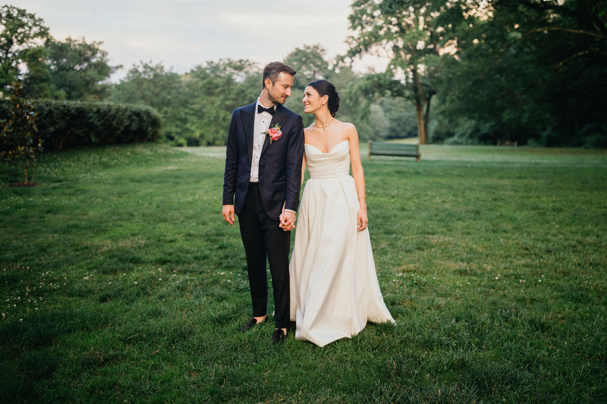 Couple holding hands, walking through the gardens after their Curtis Arboretum wedding ceremony.