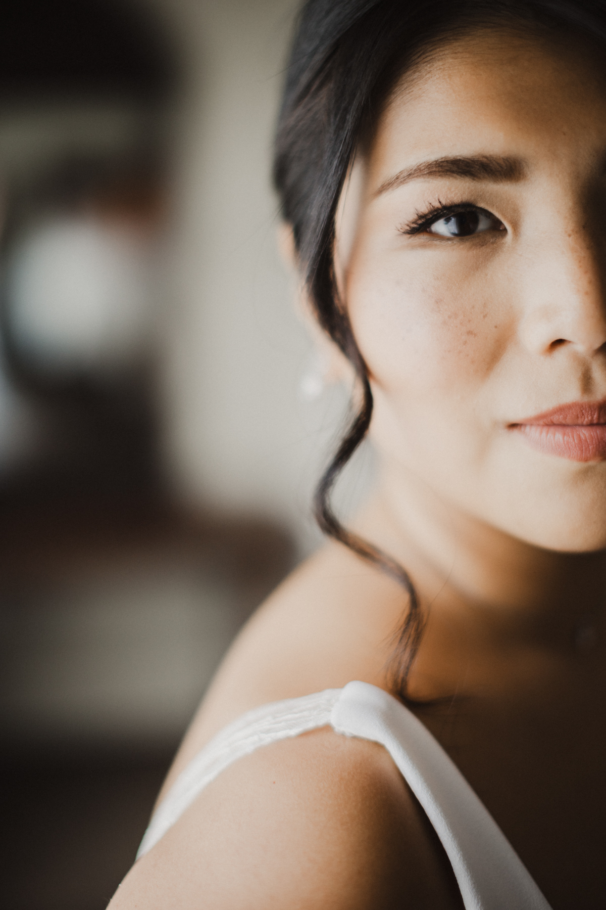 Close up shot of a bride with soft bridal makeup and curls framing her face.