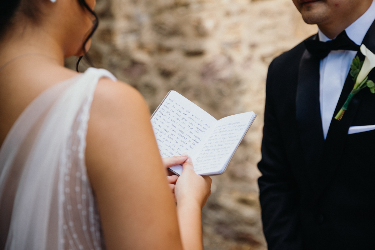 Close up of bride reading hand written vows in the courtyard garden at the James A. Michener Art Museum in Bucks County, Pennsylvania. 