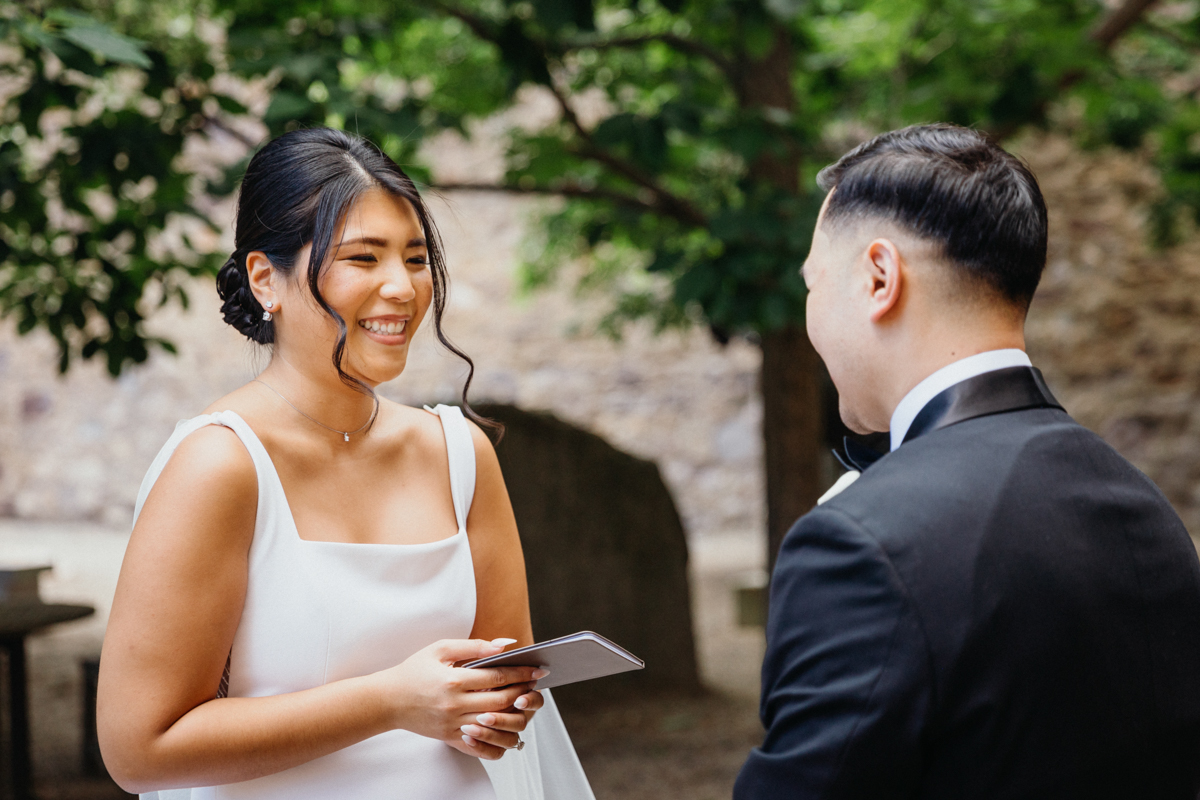 Bride and groom laughing as they exchange private vows in a museum courtyard.