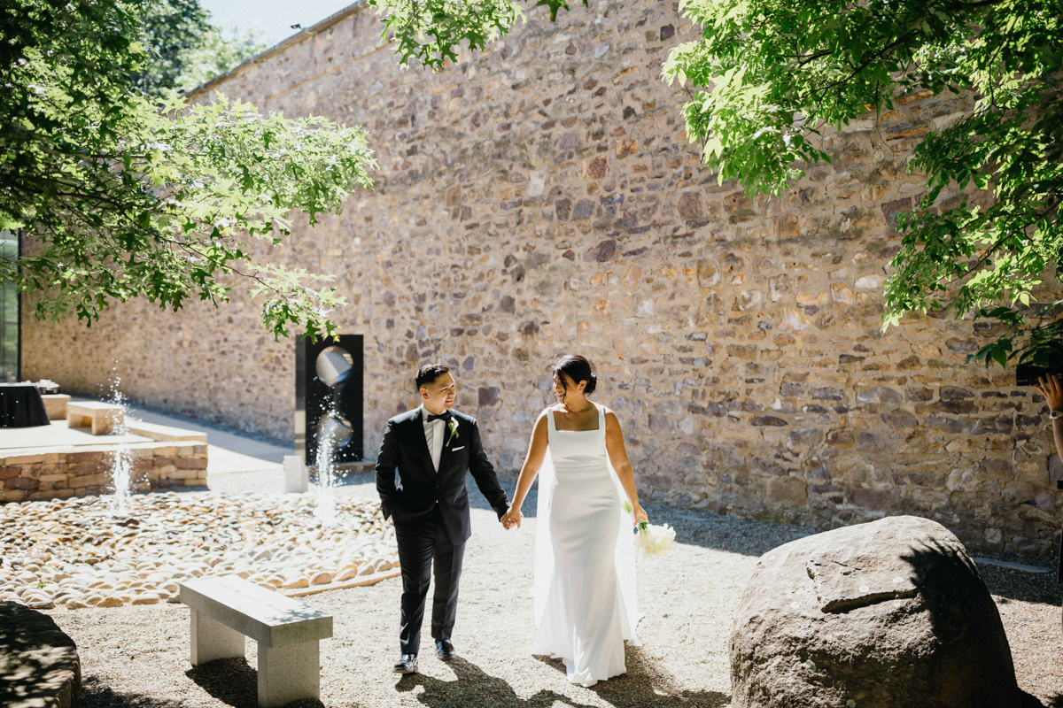 Couple on their wedding day walking through the Michener Museum courtyard holding hands.