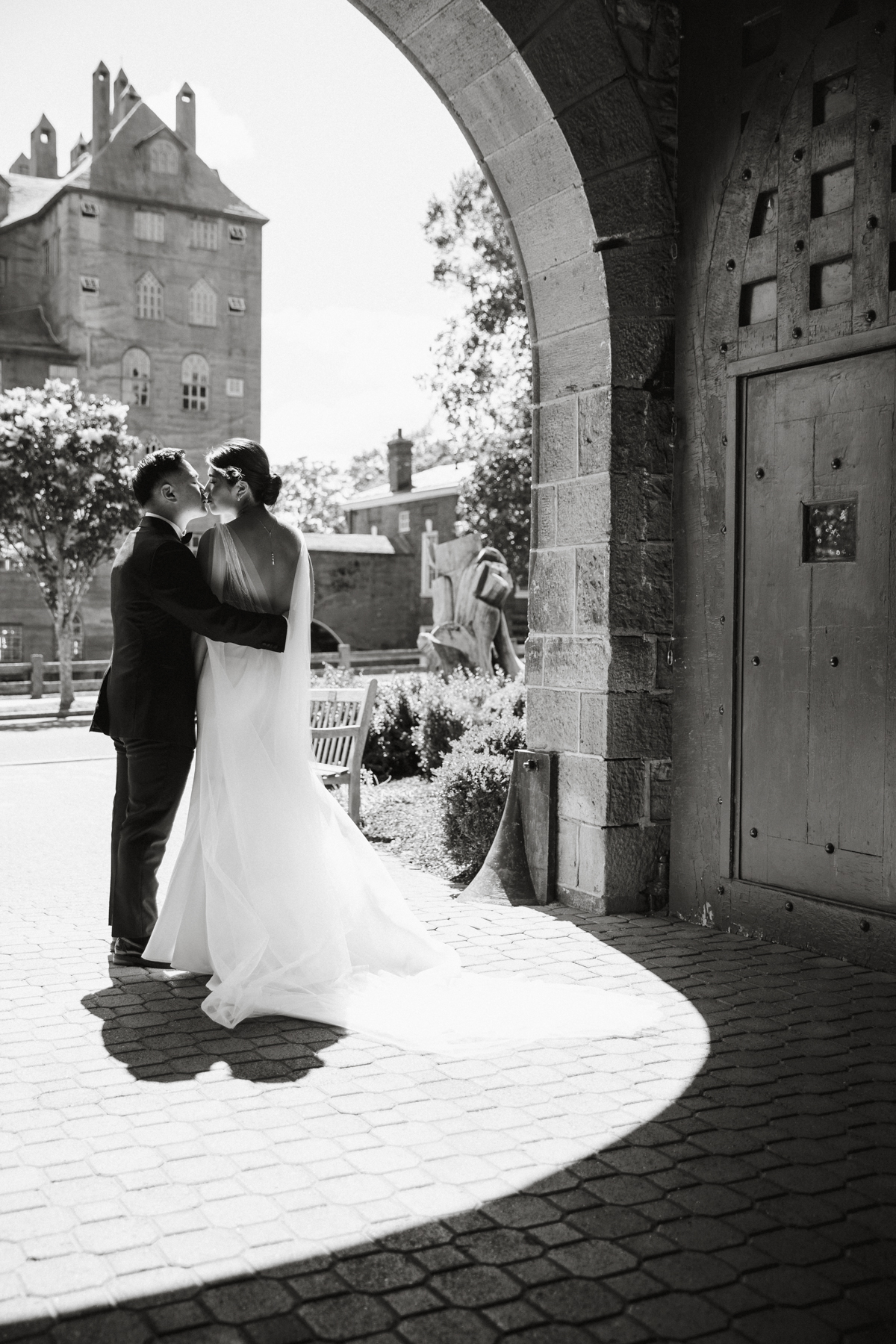 Black and white photo of wedding couple kissing under at arch at an art museum outside of Philadelphia.