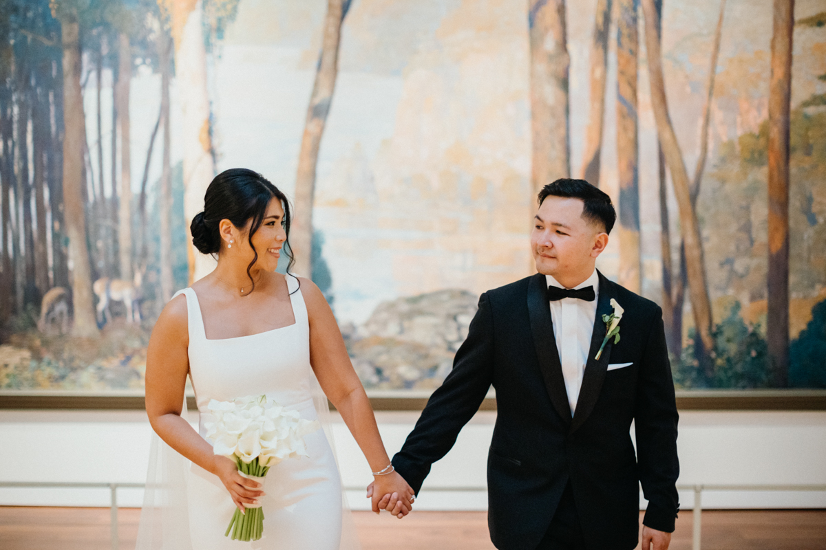 Couple holding hands in front of an impression art piece.