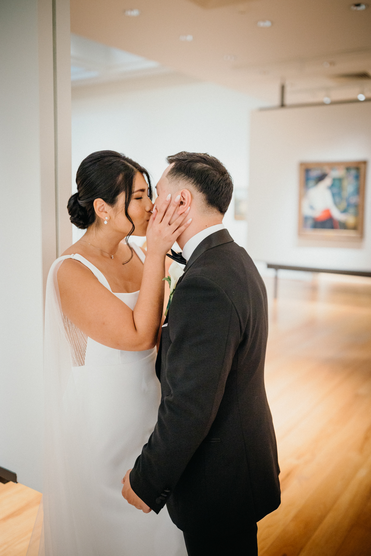 Wedding couple kissing in art gallery before their outdoor ceremony.