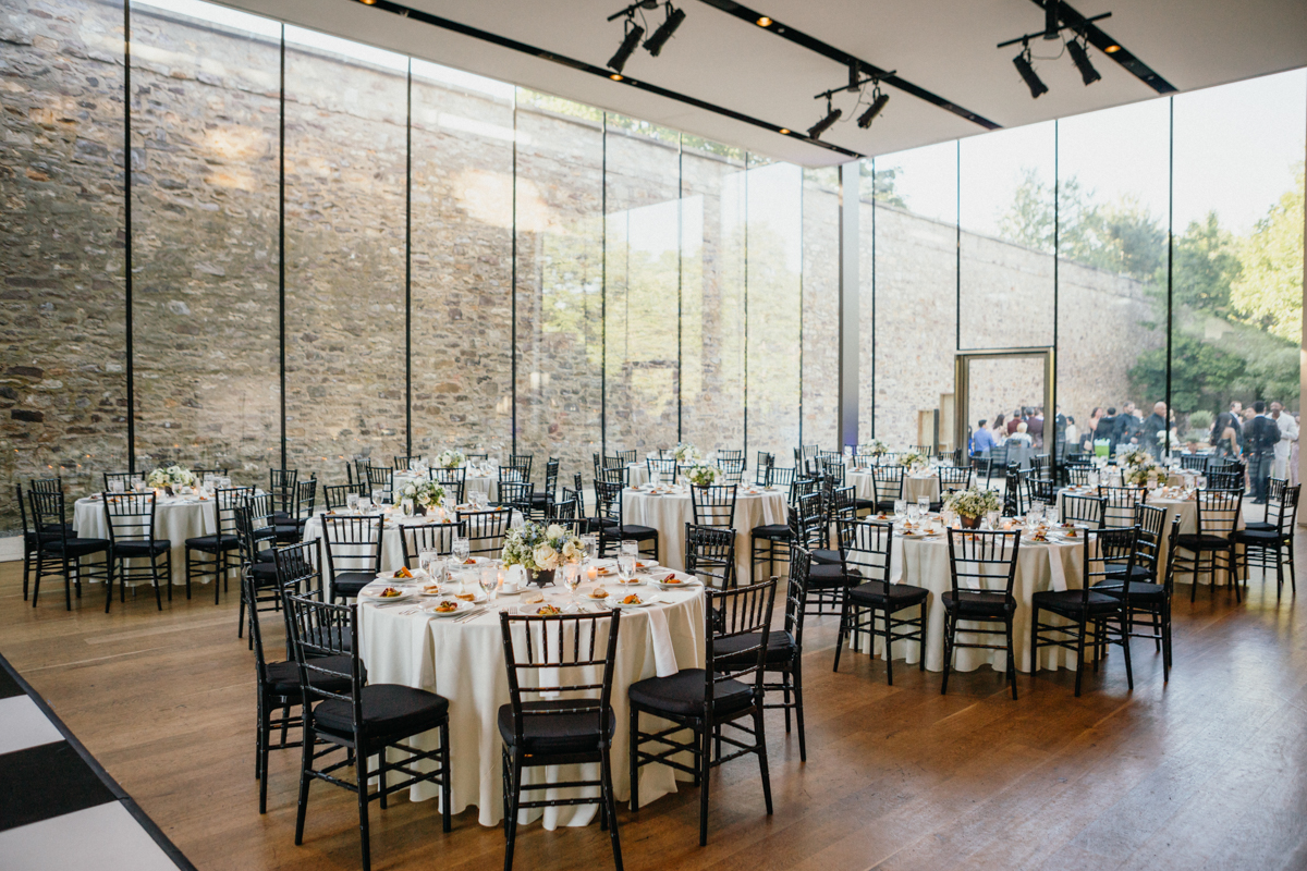 Glass walled reception space with round tables inside.