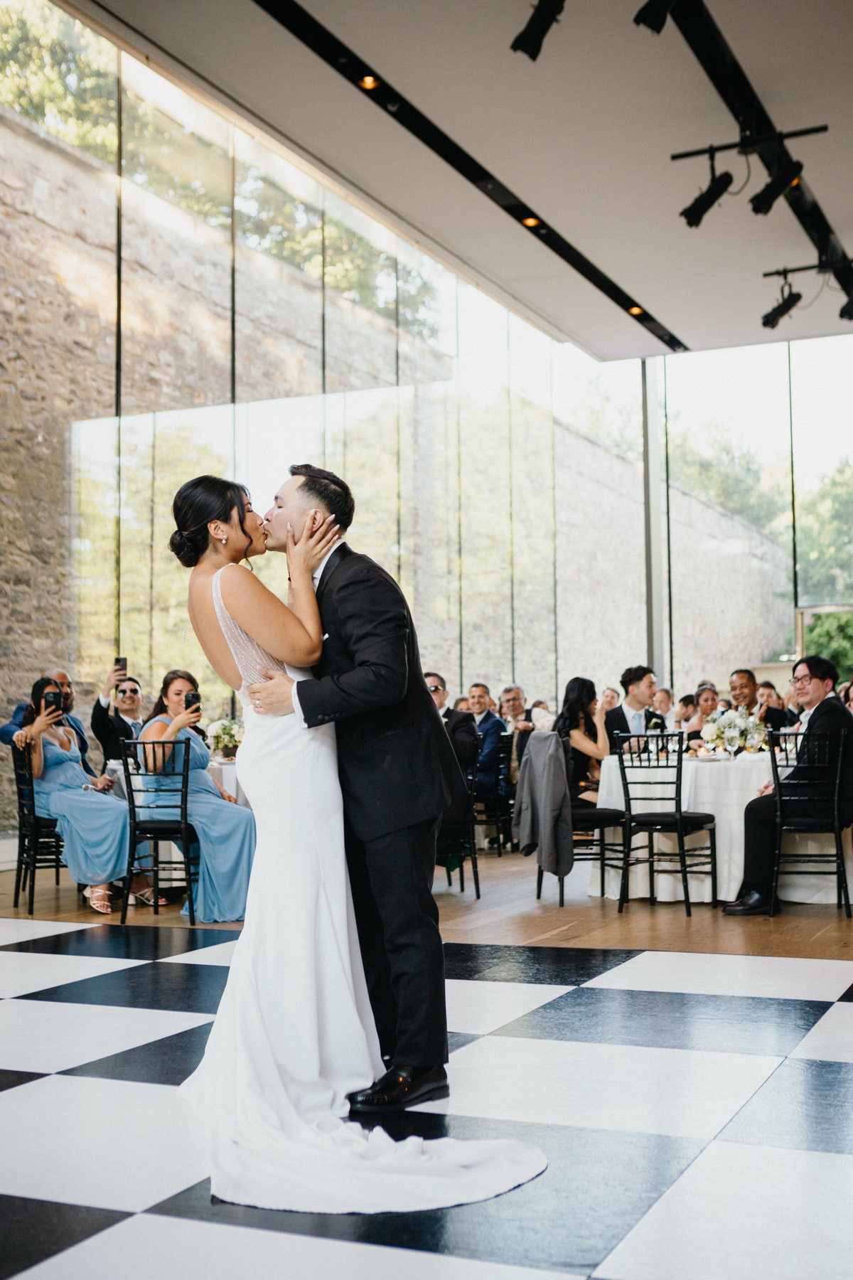 Couple sharing their first dance in a glass reception space.