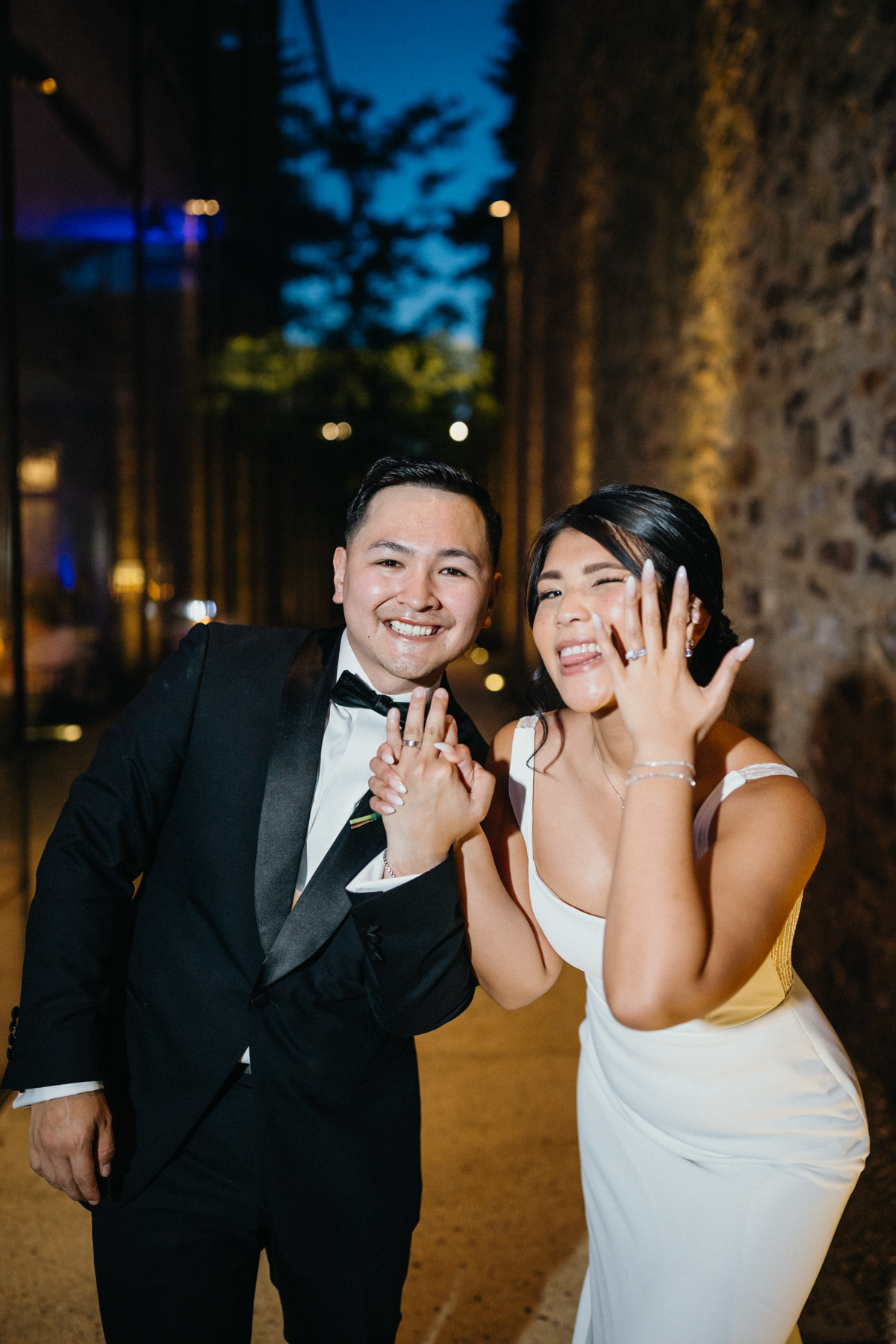 Silly couple holding up hands with new wedding rings.