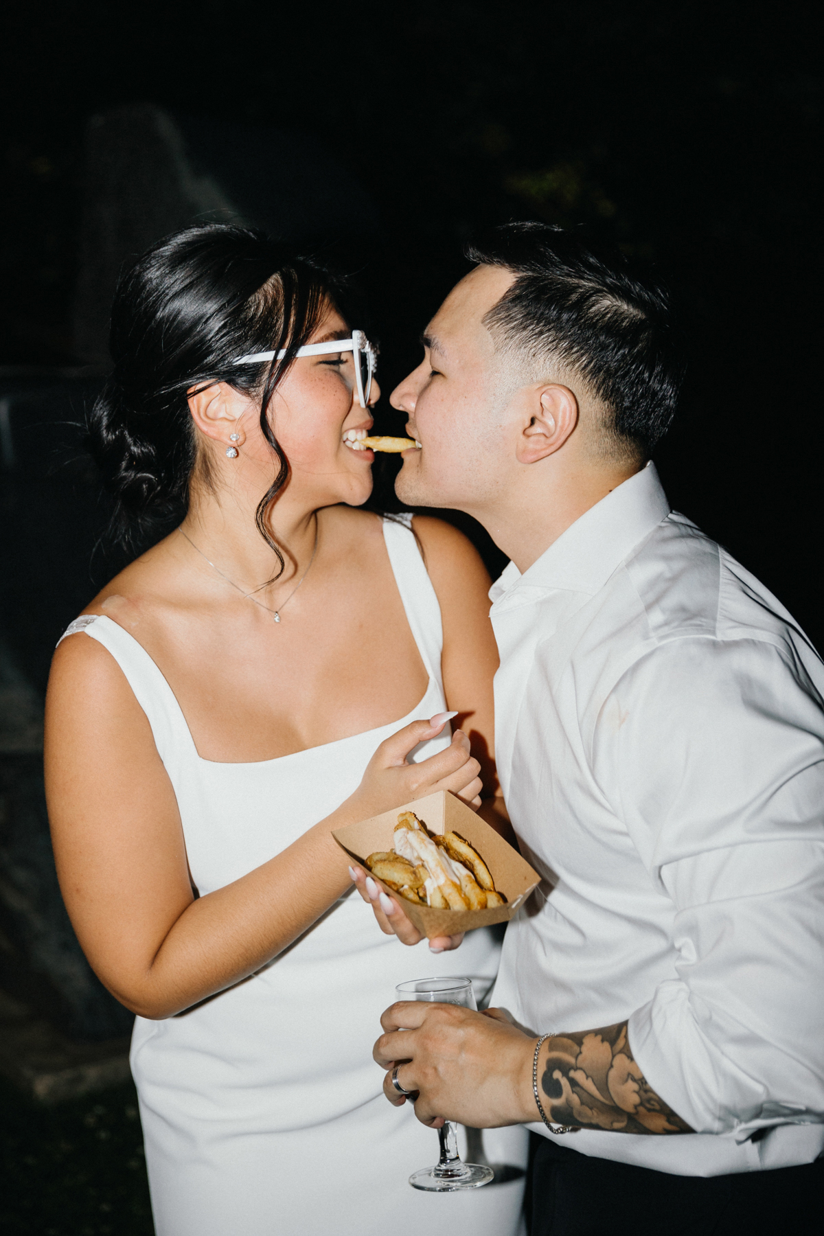 Couple sharing a french fry on the night of their wedding.