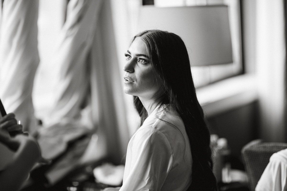 Black and white image of brunette bride getting her makeup done.