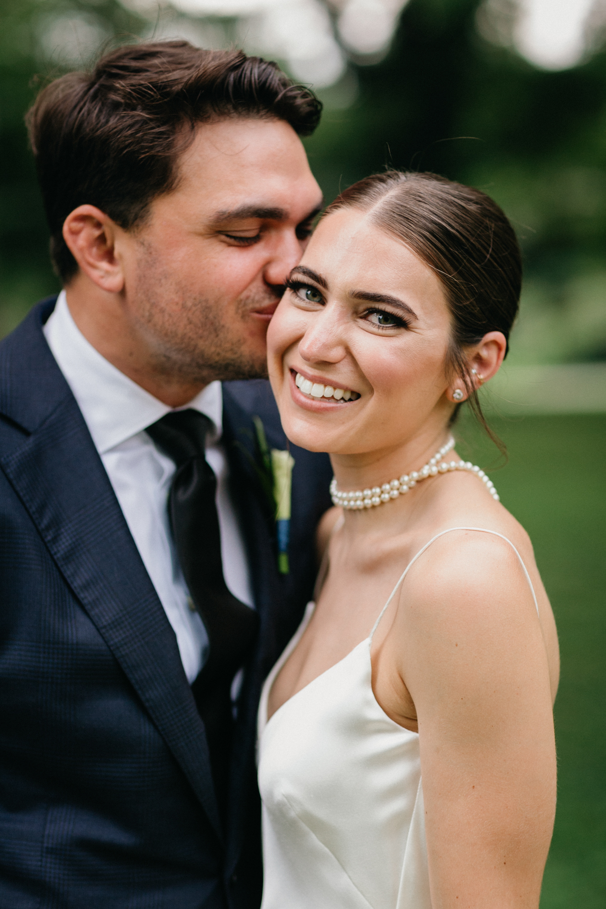 Groom kissing brides cheek as she smiles.