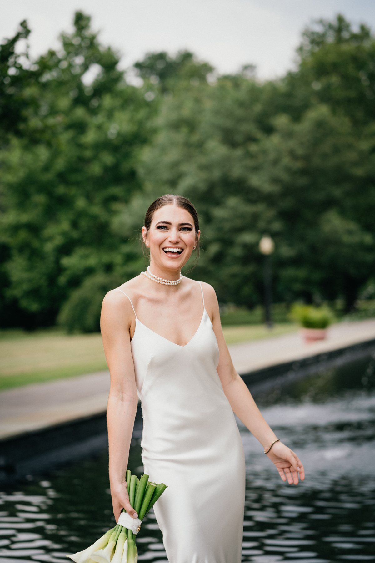 Portrait of bride in a white dress laughing with a bouquet in her hand.