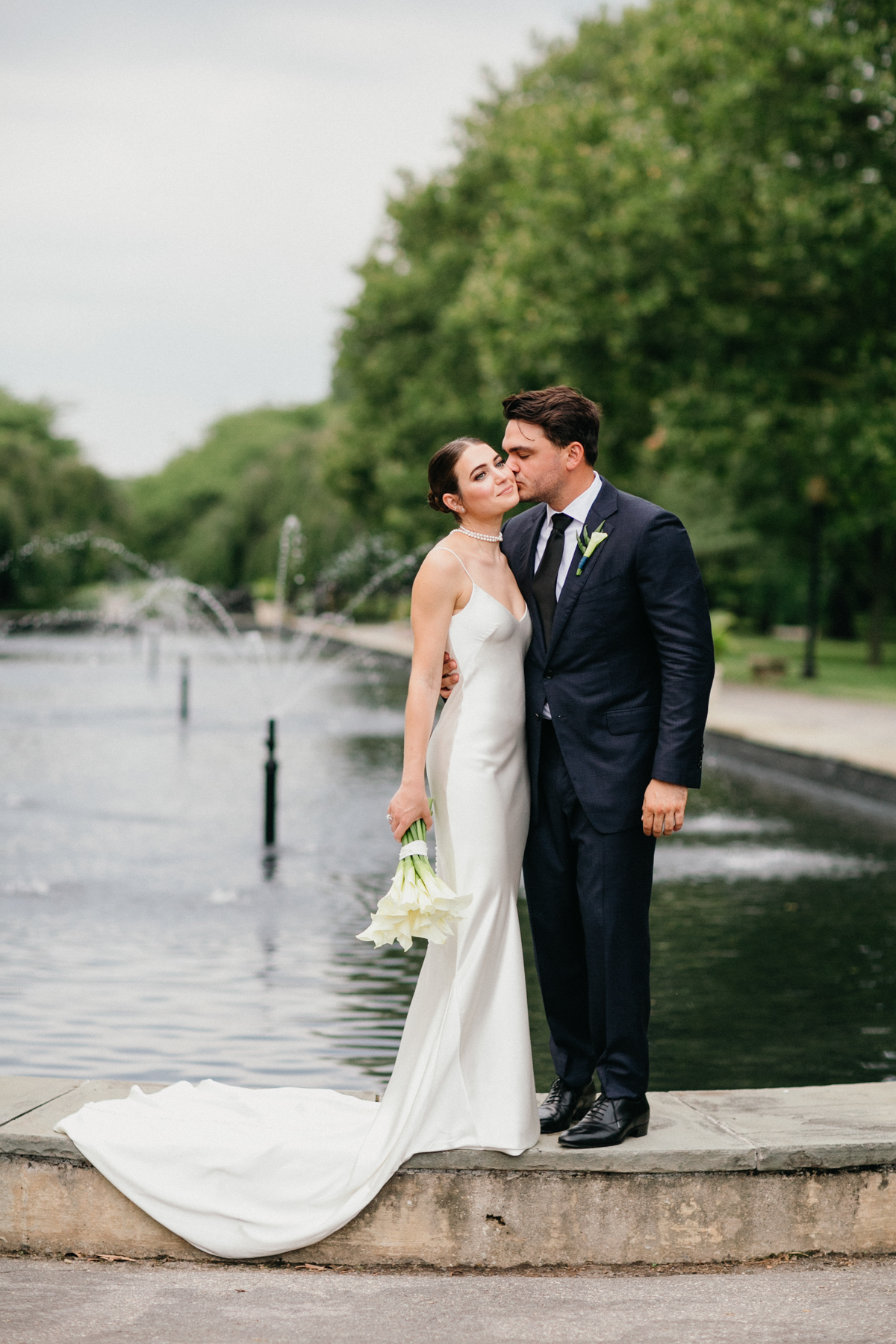 Full portrait of groom kissing brides cheek.