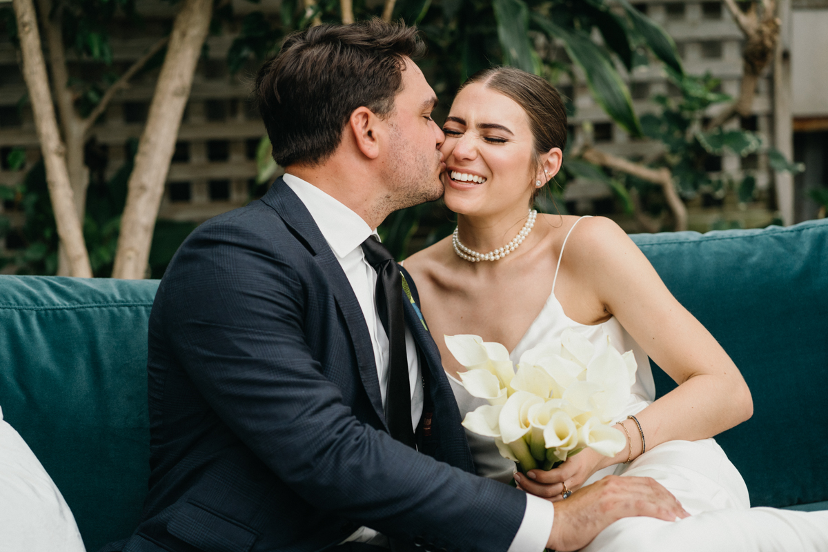 Wedding couple snuggled on a couch, laughing.