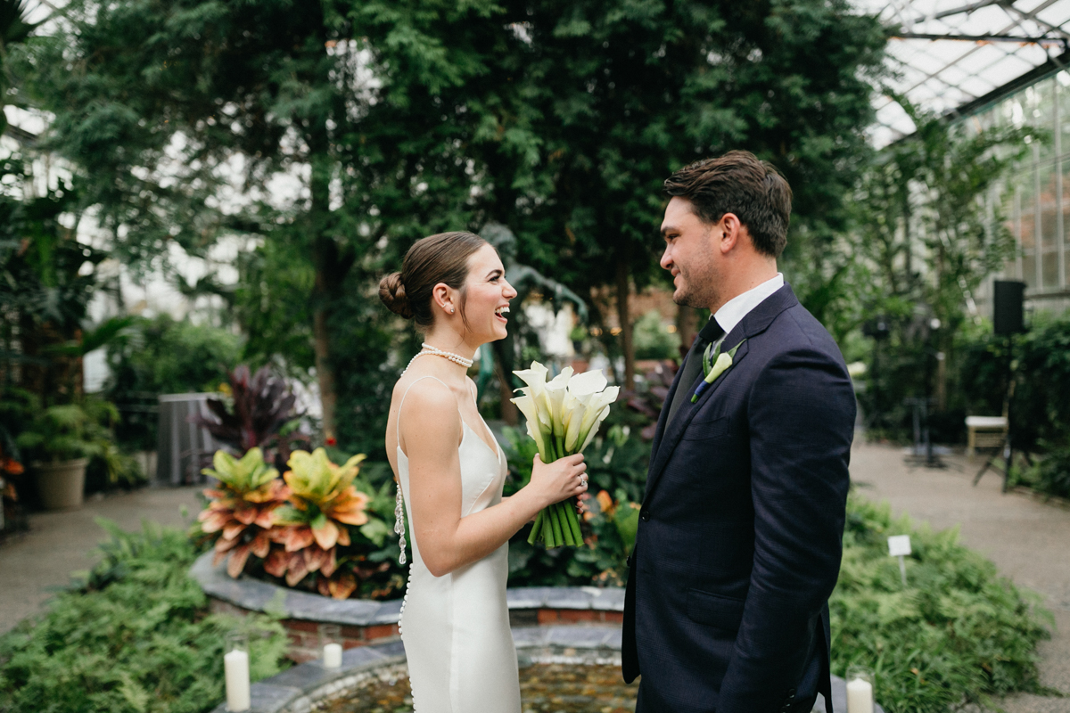 Wedding couple standing in greenhouse.