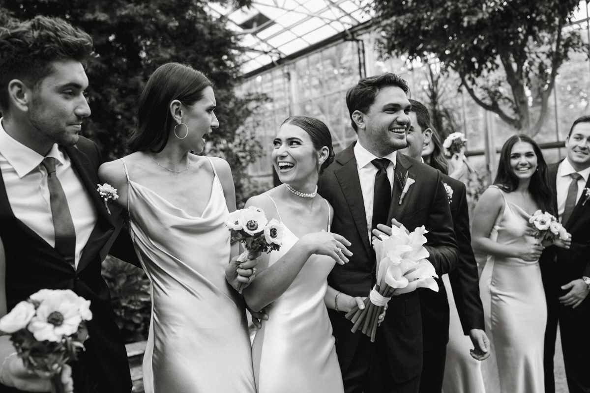 Black and white of couple laughing with bridal party.