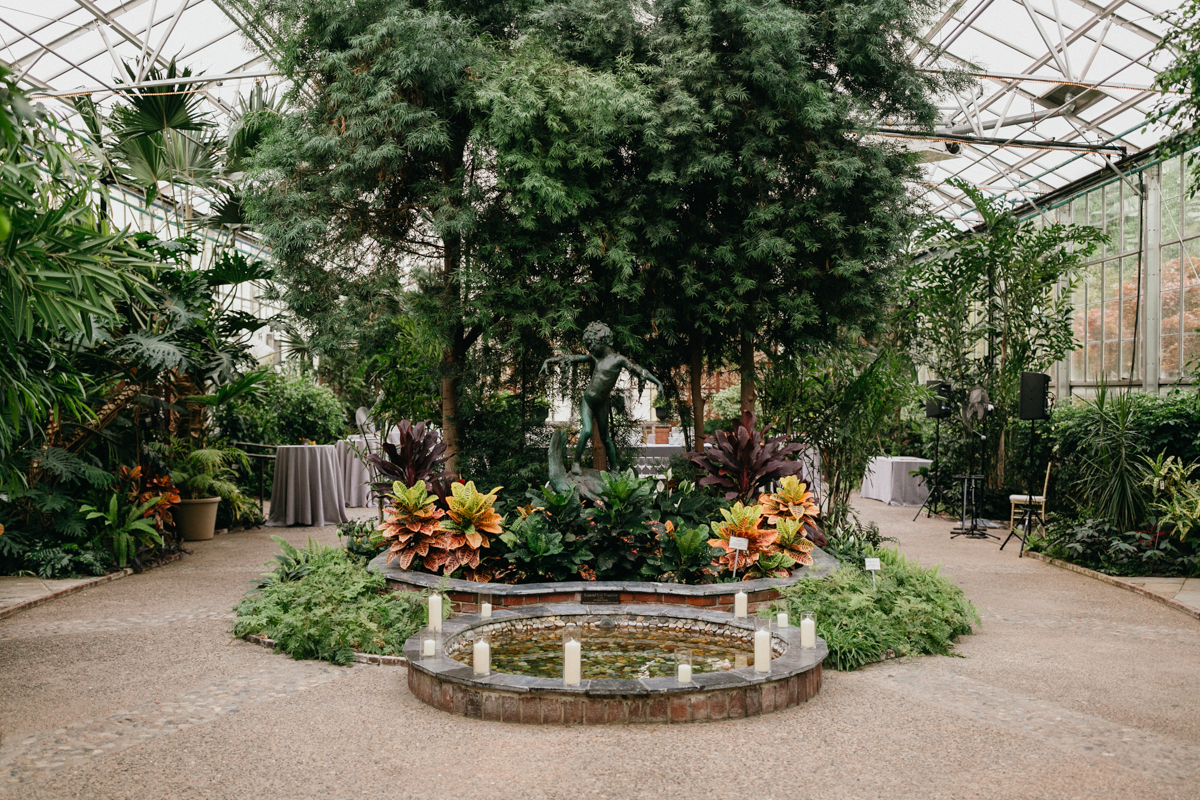 Lush greenhouse wedding space with a large tree in the center.