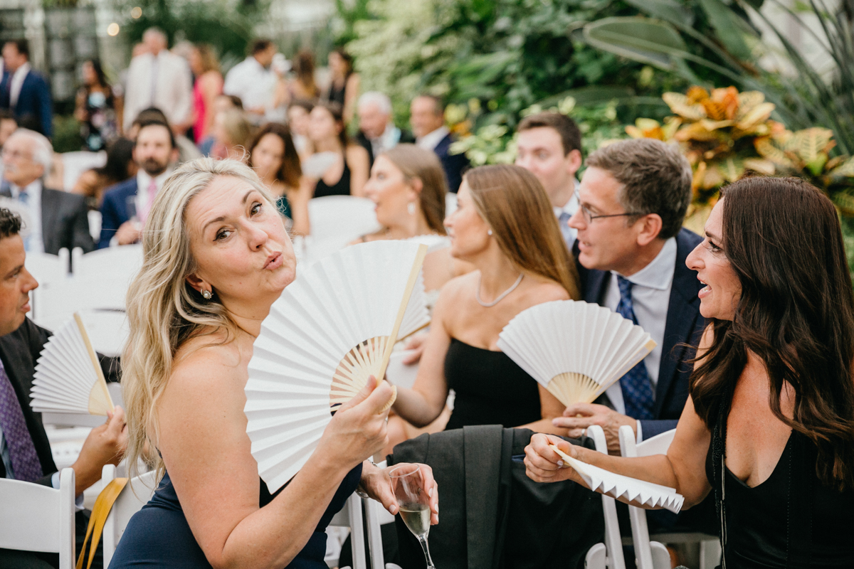 Wedding guest fanning herself with white fans.