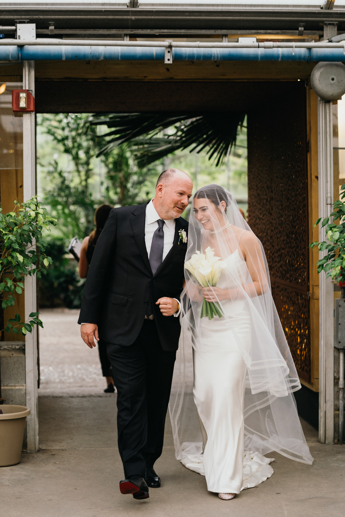 Bride and dad walking down the aisle of a greenhouse wedding.