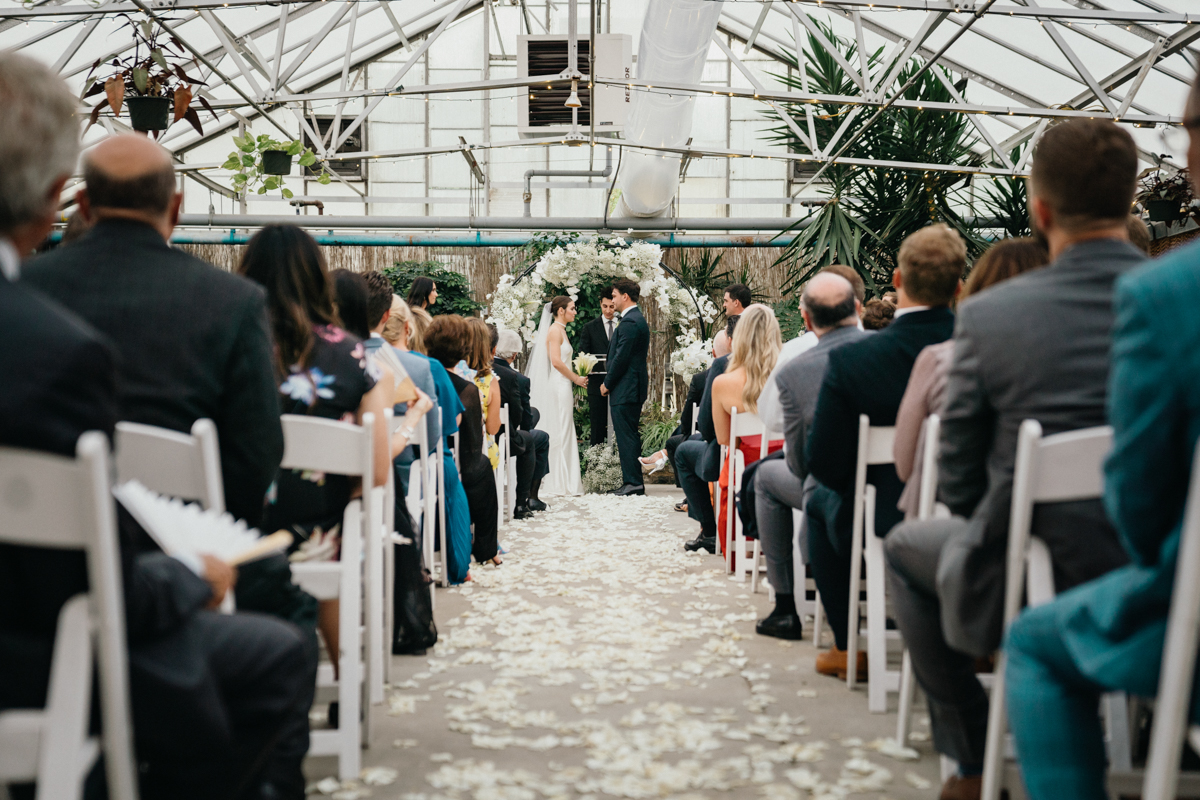 Wedding ceremony in a large white greenhouse.