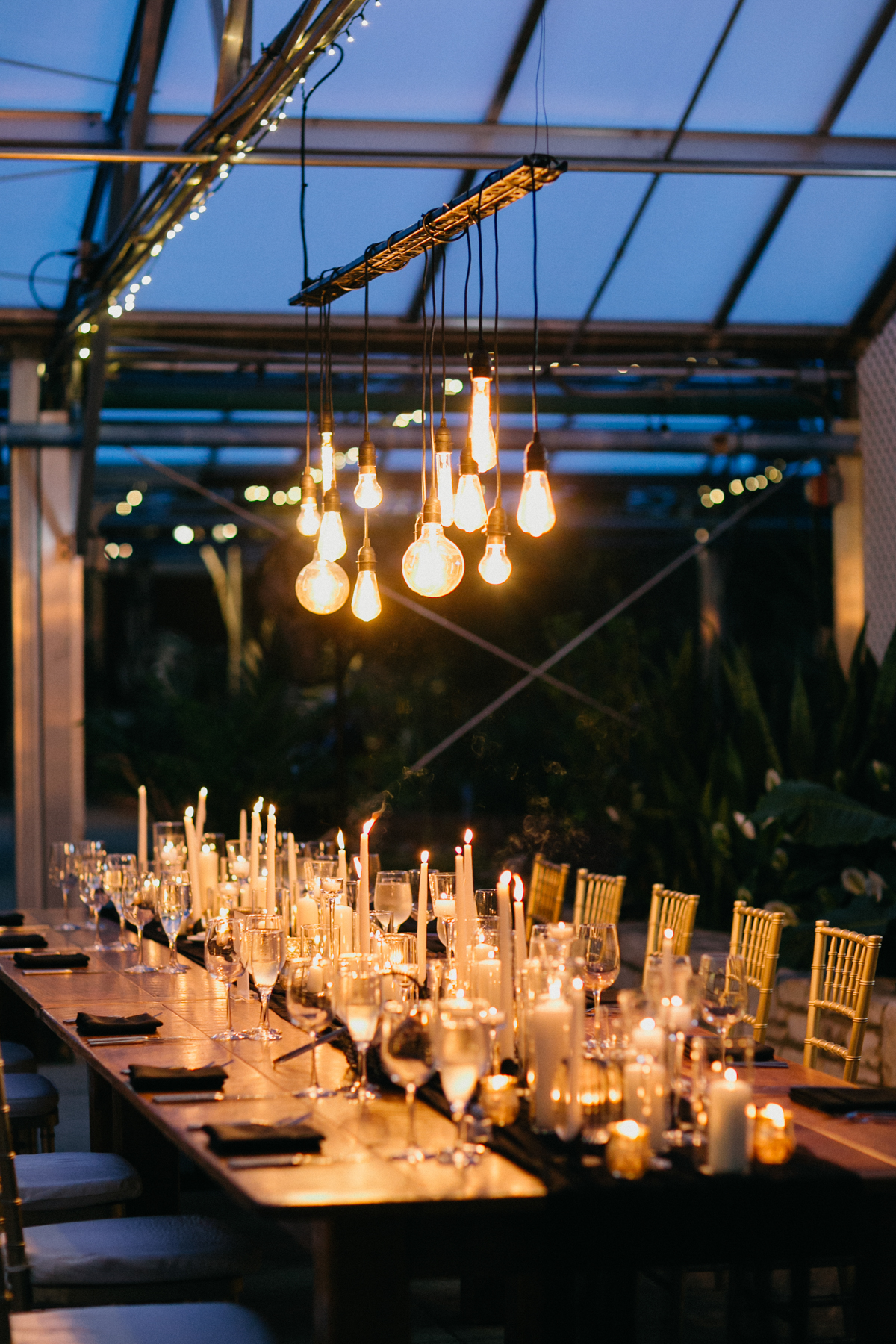 Warmly lit long rectangle reception table with candles lining the table.