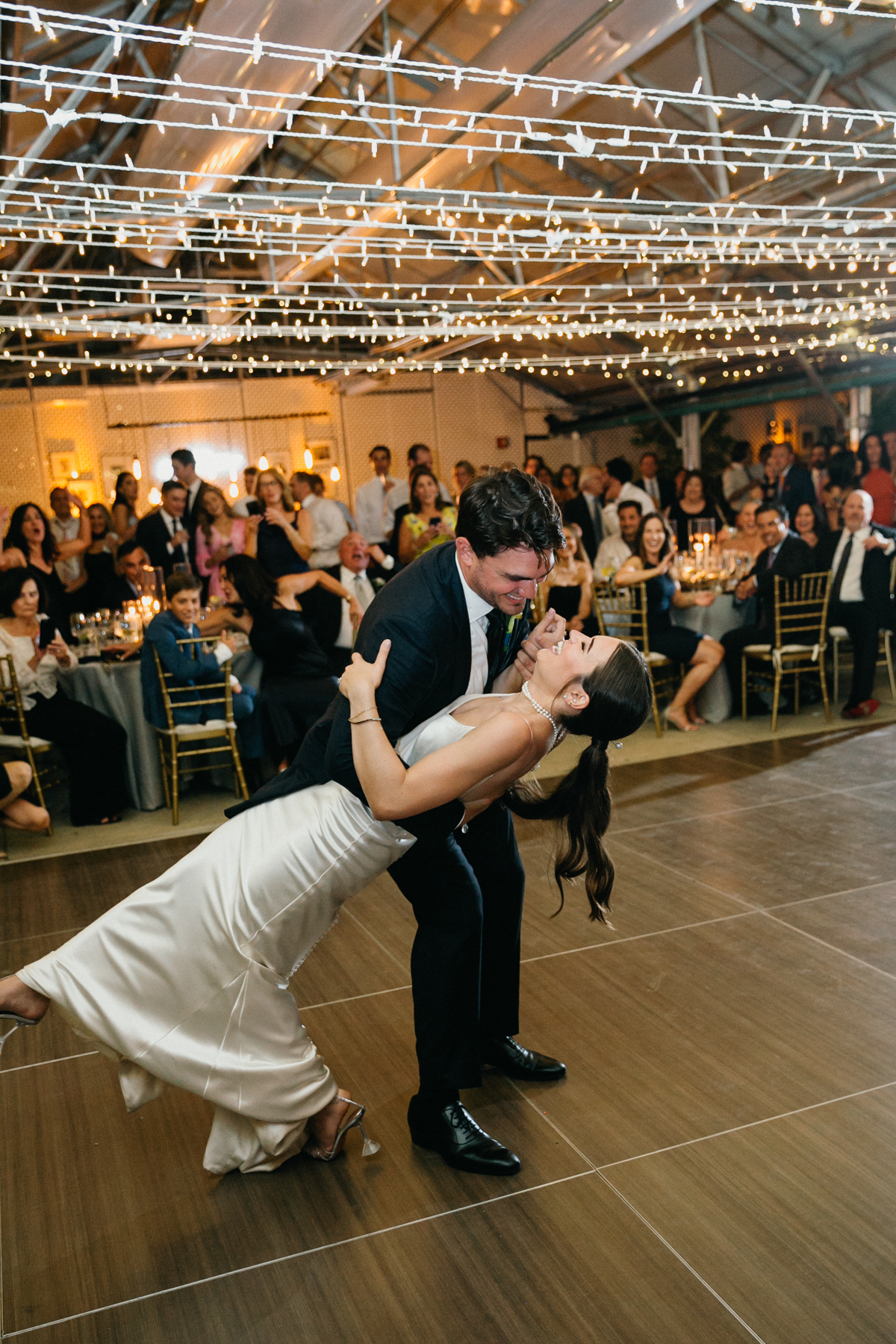 Wedding couple during their first dance. The groom is dipping his bride as they laugh.