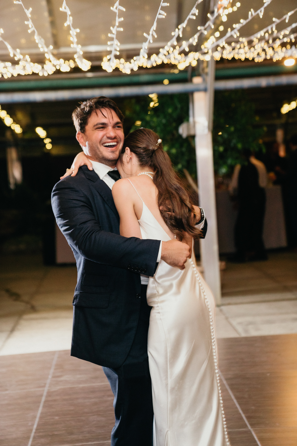 Bride falls into grooms chest as she is laughing during their first dance.