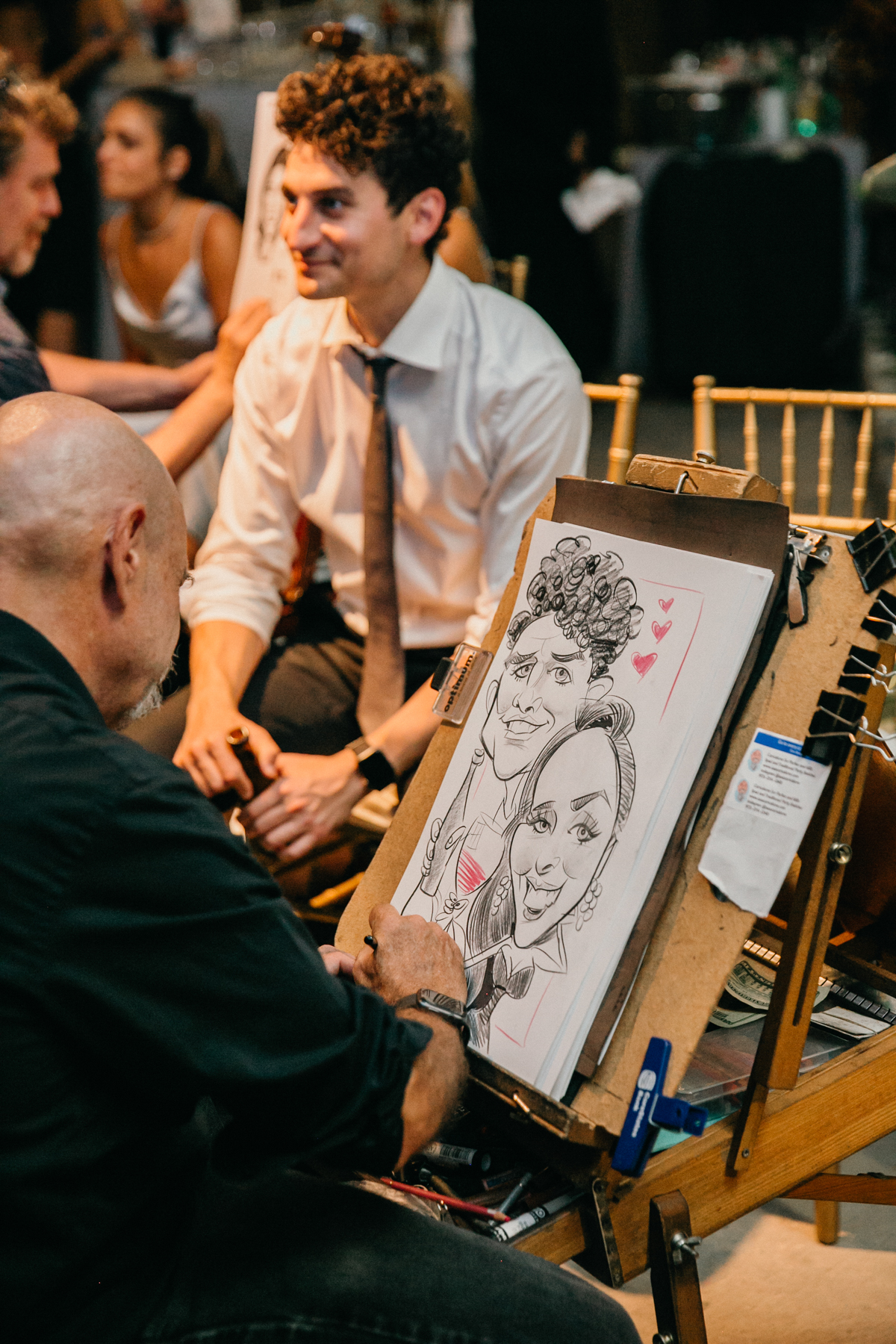 Caricature artist drawing two male guests as a wedding reception.