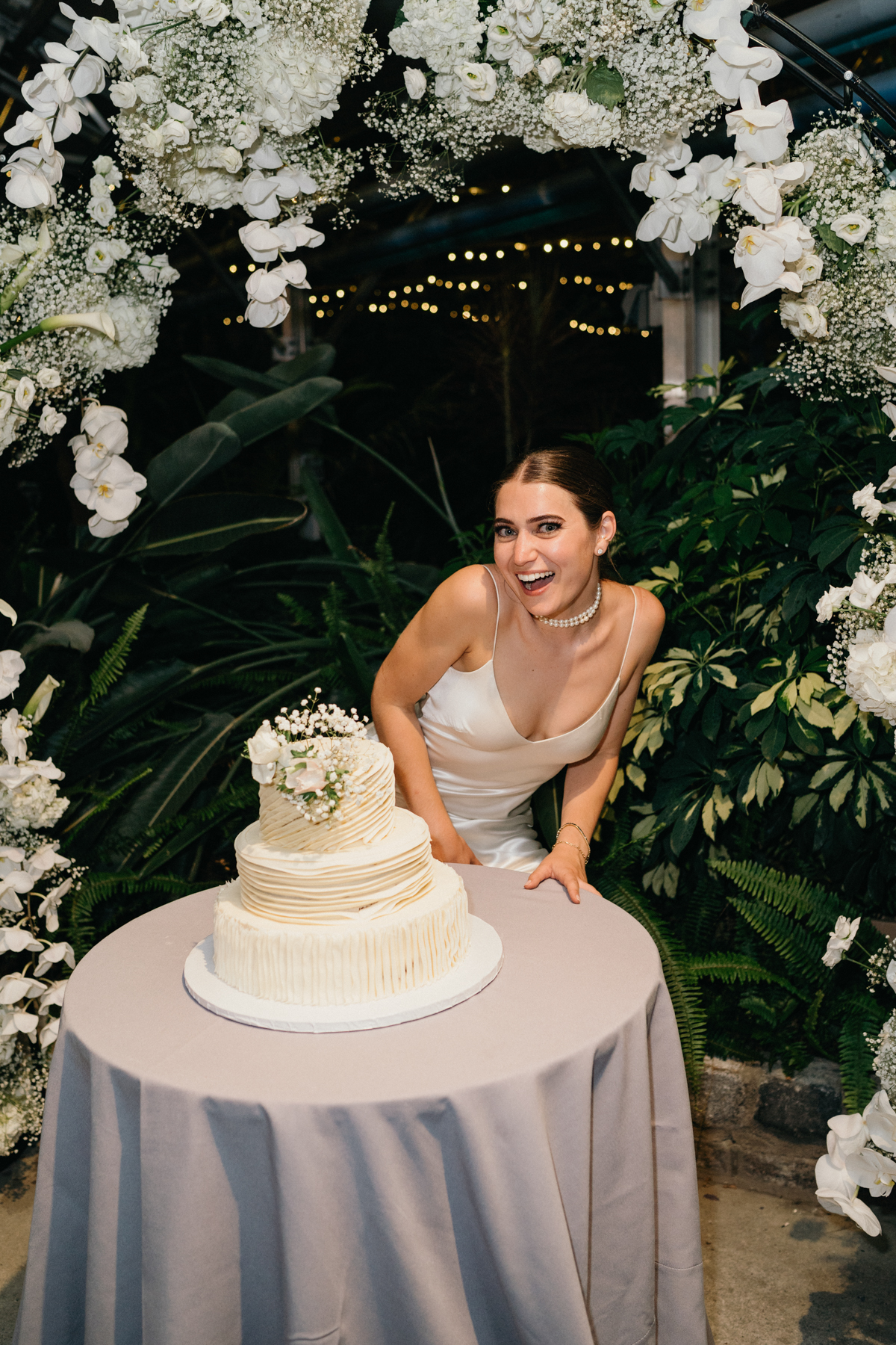 Bride crouched down, posing with her wedding cake.