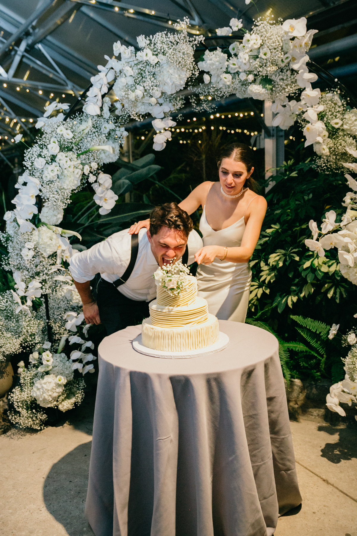 Groom taking bite out of the top of the wedding cake.