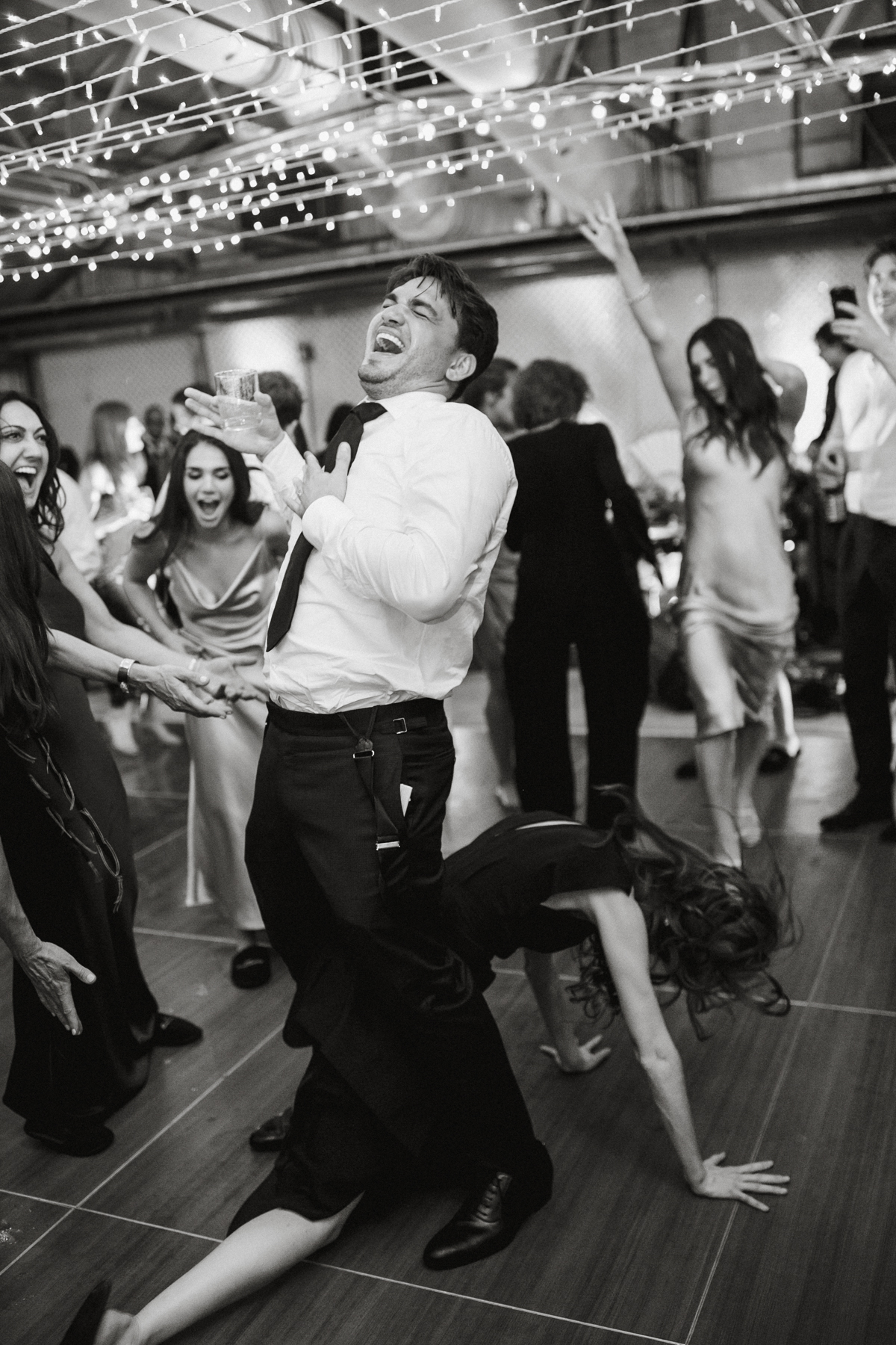 Wedding guest dancing on the floor in between grooms leg as he plays the air guitar.